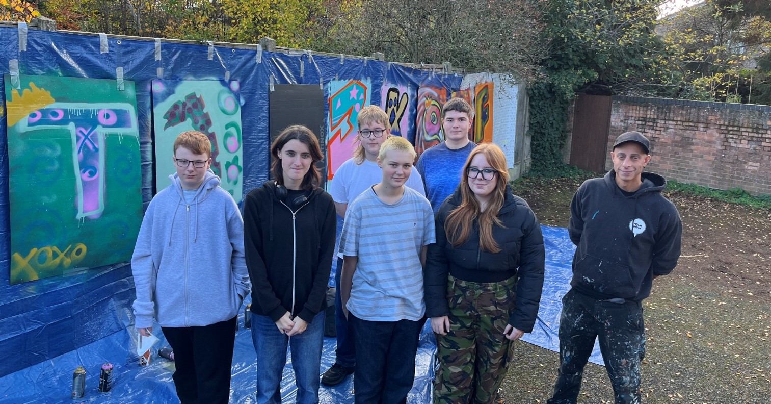 Young people stood next to the street art that they created